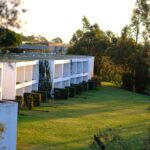 Nuno Graça Moura's 24 Row Houses at Bom Sucesso Resort showcasing a modern estate design with landscaped gardens, palm trees, and a well-maintained lawn.