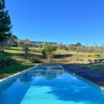 Nuno Graça Moura's 24 Row Houses at Bom Sucesso Resort showcasing a modern design with a blue swimming pool, water features, and landscaped surroundings providing shade and shadow.