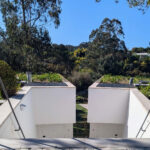 Nuno Graça Moura's 24 Row Houses at Bom Sucesso Resort showcasing a modern concrete structure with integrated landscaping, ample daylighting, and a shadowed walkway.