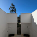 Nuno Graça Moura's 24 Row Houses at Bom Sucesso Resort showcasing a modern design with concrete walls, tiled walkways, and ample daylighting through large windows.
