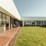 Nuno Graça Moura's 8 Villas at Bom Sucesso Resort showcasing a modern design with a focus on daylighting, featuring expansive flooring, shaded courtyards, and artificial turf lawns.