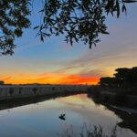 Nuno Graça Moura's Bar Code 1 - 30 Row Houses at Bom Sucesso Resort with a modern design featuring a waterway reflecting the sunset, creating a serene evening atmosphere.
