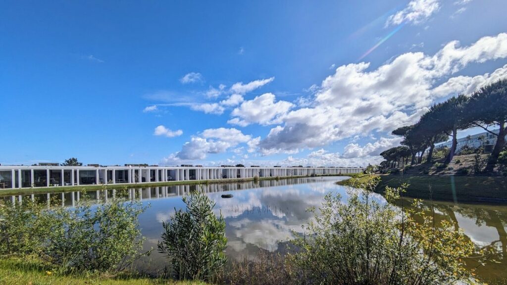 Nuno Graça Moura's Bar Code 1 - 30 Row Houses at Bom Sucesso Resort with a modern design featuring a waterway reflecting the sunset, creating a serene evening atmosphere.