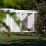 Nuno Graça Moura's Bar Code 2 - 12 Row Houses at Bom Sucesso Resort showcasing a modern design with a landscaped garden, outdoor structures, and a shaded lawn area.