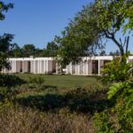 Nuno Graça Moura's Bar Code 2 - 12 Row Houses at Bom Sucesso Resort showcasing a modern design with a columned structure, landscaped gardens, and a well-maintained lawn.