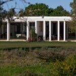 Nuno Graça Moura's Bar Code 2 - 12 Row Houses at Bom Sucesso Resort showcasing a modern design with a shaded outdoor structure, landscaped lawn, and expansive backyard.
