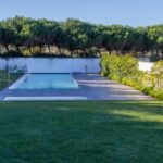 Nuno Graça Moura's Bar Code 2 - 12 Row Houses at Bom Sucesso Resort showcasing a modern design with a swimming pool, landscaped garden, composite materials, and a shaded backyard with artificial turf.