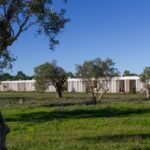 Nuno Graça Moura's Bar Code 2 - 12 Row Houses at Bom Sucesso Resort showcasing a modern design with a landscaped garden, lawn, and shrubbery surrounding the estate.