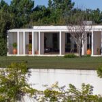 Nuno Graça Moura's Bar Code 2 - 12 Row Houses at Bom Sucesso Resort showcasing a modern design with concrete columns, landscaped lawns, and outdoor structures.