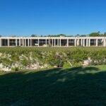 Nuno Graça Moura's Bar Code 2 - 12 Row Houses at Bom Sucesso Resort showcasing a series of columns, a landscaped garden, and a shaded courtyard with a well-maintained lawn and plantation.