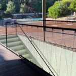 Nuno Graça Moura's Pool Bar at Bom Sucesso Resort showcasing a sleek design with composite material, metal handrails, and a steel walkway integrated into the sloped landscape.
