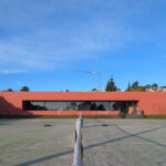 Nuno Graça Moura's Tennis Club at Bom Sucesso Resort showcasing a modern design with concrete structures, shaded areas, and an adjacent driveway.
