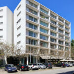 Adalberto Dias’s Casas Brancas featuring a high-rise mixed-use building with a glass façade, shaded balconies, and a metropolitan apartment and commercial condominium design.