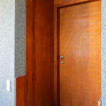 Adalberto Dias’s Casas Brancas showcasing a modern home entrance with stained wood door, composite wood flooring, and brown hardwood wall panels.