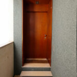 Adalberto Dias’s Casas Brancas showcasing a modern home door with brown stained hardwood flooring and composite wood walls.