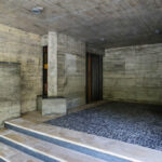 Agostinho Ricca’s Igreja do Foco / Igreja de Nossa Senhora da Boavista showcasing a modern design with grey concrete walls, wooden plank flooring, and composite materials creating a minimalist interior.