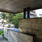 Agostinho Ricca’s Igreja do Foco / Igreja de Nossa Senhora da Boavista showcasing a modern design with exposed concrete beams, wood-stained composite materials, and strategic daylighting under a shaded overpass structure.