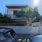 Alcino Soutinho’s Unifamiliar em Paços de Brandão showcasing a modern residential home with a balcony, metal fence and gate, shaded areas, and ample daylighting.