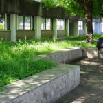 Alexandre Alves Costa and Sérgio Fernandez’s Escola de Ciências Sociais at Universidade do Minho showcasing a landscaped public space with concrete walkways, shaded garden areas, groundcover, and green lawns surrounding the modern building.
