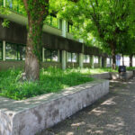 Alexandre Alves Costa and Sérgio Fernandez’s design of Escola de Ciências Sociais, Universidade do Minho, showcasing a concrete public space with shaded walkways, landscaped gardens, groundcover, and a well-maintained lawn.