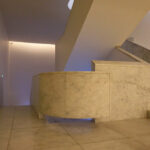 Museum of International Contemporary Sculpture designed by Álvaro Siza Vieira and Eduardo Souto de Moura, showcasing interior design with composite tile flooring, textured walls, minimalist ceiling light fixtures, and a sleek staircase.