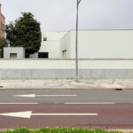 Álvaro Siza Vieira’s Casa Armanda Passos showcasing a minimalist concrete façade with clean lines, composite material walls, and a sidewalk adjacent to an asphalt road surface in a residential area.