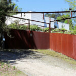 Álvaro Siza Vieira’s Casa David Vieira de Castro showcasing a rustic backyard with wood and metal fencing, featuring iron wire elements and weathered rust textures.