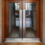 Álvaro Siza Vieira's Casa Ferreira da Costa / Casa Miranda dos Santos showcasing a wooden door with a sleek handle, hardwood flooring, and a glass element enhancing the modern design.