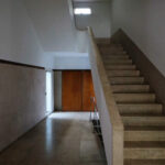 Álvaro Siza Vieira's Casa Ferreira da Costa / Casa Miranda dos Santos showcasing a minimalist design with wooden flooring, concrete walls, and a staircase with wood stain accents.