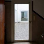 Álvaro Siza Vieira's Casa Ferreira da Costa / Casa Miranda dos Santos showcasing a modern design with concrete walls, wooden flooring, and large home doors allowing ample daylighting.