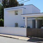 Álvaro Siza Vieira’s Casa Luís Figueiredo showcasing a minimalist concrete façade with plastered walls, a composite material balcony, and a modern residential gate.