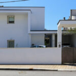 Álvaro Siza Vieira’s Casa Luís Figueiredo showcasing a grey concrete façade with composite material walls and a minimalist residential design featuring a prominent door.