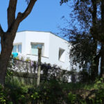 Álvaro Siza Vieira’s Casa Luís Figueiredo showcasing a minimalist home with clean white walls, integrated landscaping featuring shrubs, and a well-maintained yard.