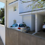 Álvaro Siza Vieira’s Casa Luís Figueiredo showcasing a residential home with concrete and plaster composite materials, featuring shaded balconies, a driveway, and ample daylighting.