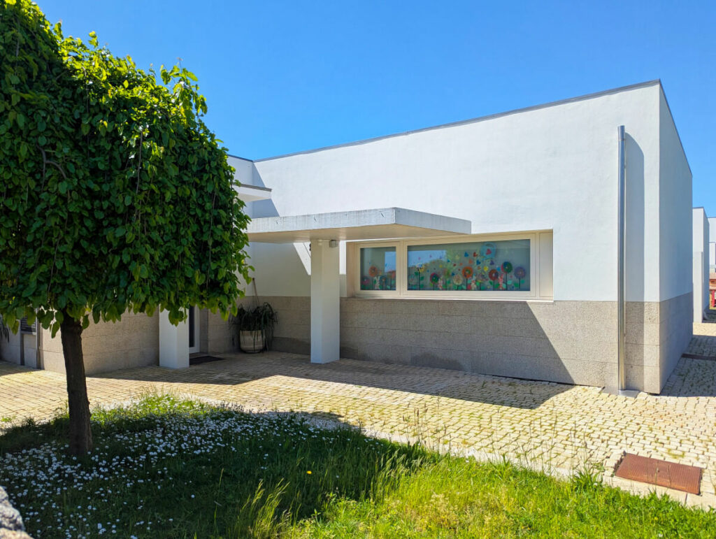 Álvaro Siza Vieira’s Centro Social e Paroquial de Sao Miguel de Ceide showcasing a concrete structure with composite material walls, shaded public walkways, and an integrated sidewalk in a modern architectural design.