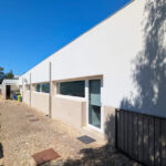Álvaro Siza Vieira’s Centro Social e Paroquial de Sao Miguel de Ceide showcasing a concrete and plaster façade with composite materials, shaded walkways, and strategic daylighting elements.
