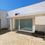 Álvaro Siza Vieira’s Centro Social e Paroquial de Sao Miguel de Ceide showcasing minimalist concrete walls, composite material flooring, large doors, and natural daylighting through architectural openings.