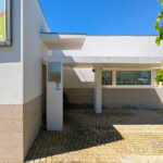 Álvaro Siza Vieira’s Centro Social e Paroquial de Sao Miguel de Ceide showcasing a minimalist concrete and plaster façade with tiled flooring and strategic daylighting creating shaded interior spaces.