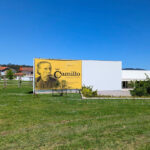Álvaro Siza Vieira’s Centro de Estudos Camilianos showcasing a minimalist design with clean white walls, large rectangular windows, and a flat roof integrating advertising signage.