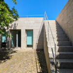 Álvaro Siza Vieira’s Centro de Estudos Camilianos showcasing a concrete structure with composite material walls, daylighting through walkways, stairs casting shadows, and minimalist architectural elements.