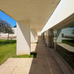 Álvaro Siza Vieira’s Centro de Estudos Camilianos showcasing a concrete structure with shaded walkways, surrounded by a green lawn and designed to maximize natural daylighting.