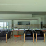 Álvaro Siza Vieira’s Centro de Estudos Camilianos interior showcasing tile flooring, minimalist furniture, large glass windows allowing natural daylighting, and a clean, modern ceiling design.