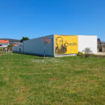 Álvaro Siza Vieira’s Centro de Estudos Camilianos showcasing a minimalist design with clean white walls, large glass windows, and a landscaped lawn surrounding the building.