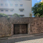 Álvaro Siza Vieira’s Edificio de Escritónos showcasing a minimalist design with composite concrete and stone walls, featuring flagstone elements and strategic daylighting.