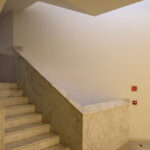 Álvaro Siza Vieira and Eduardo Souto de Moura’s Museum of International Contemporary Sculpture showcasing a minimalist interior with plaster walls, tile flooring, wooden stairs, and ample daylighting through large windows.