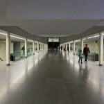 Álvaro Siza Vieira’s Estação de Metro São Bento showcasing a clean subway walkway with tiled flooring, concrete ceiling, and silver composite material elements.