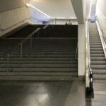 Álvaro Siza Vieira’s Estação de Metro São Bento showcasing a modern interior with black and grey composite flooring, metal handrails, stairs, and escalators under a sleek ceiling.
