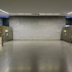 Álvaro Siza Vieira’s Estação de Metro São Bento showcasing a minimalist concrete interior with grey composite walls, silver light fixtures, and polished flooring under a sleek ceiling design.