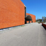 Álvaro Siza Vieira’s Pavilhão Multiusos de Gondomar showcasing a modern design with composite materials, detailed brickwork, and strategic daylighting creating dynamic shadows on the building façade.