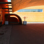 Álvaro Siza Vieira’s Pavilhão Multiusos de Gondomar showcasing an orange composite material exterior with large daylighting elements.